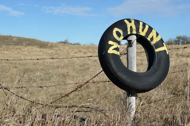 No Hunting tire sign on a fence